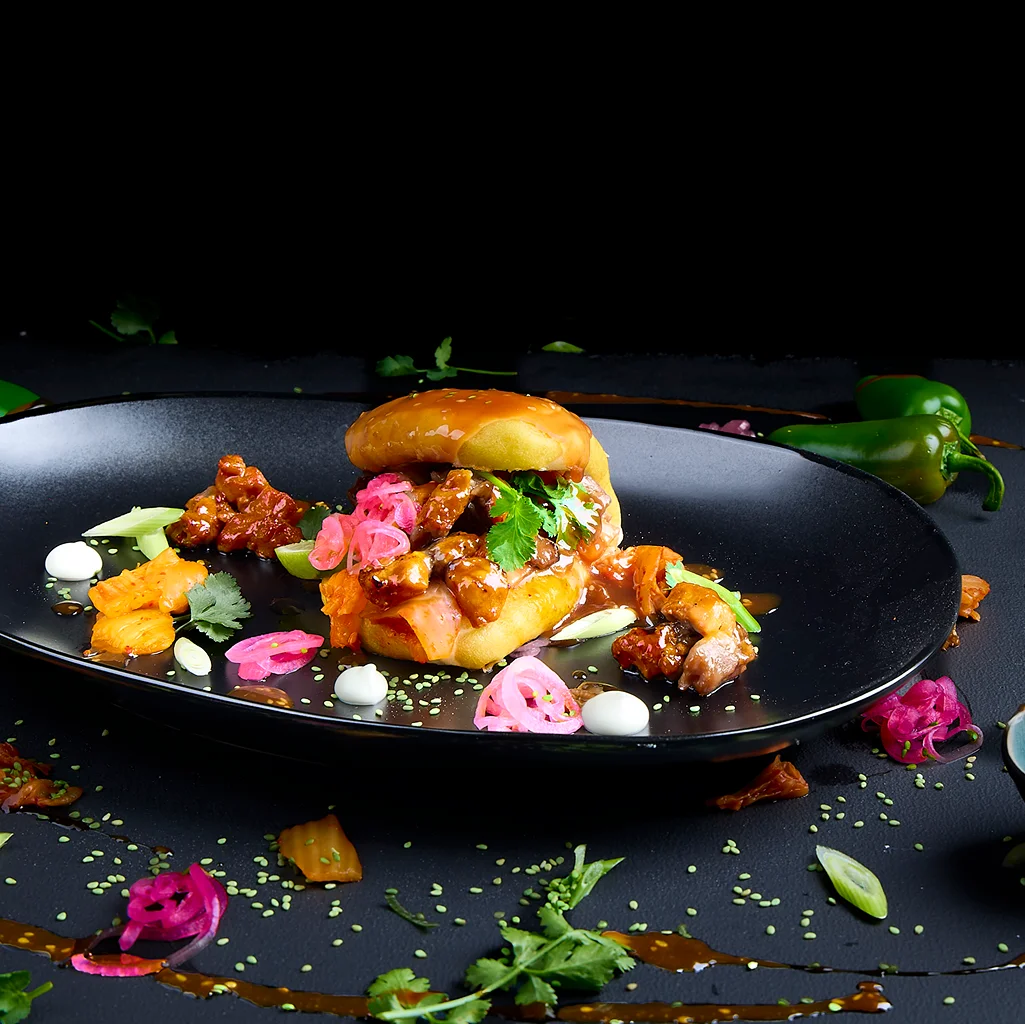 Korean Fusion Bao Bun mit Hähnchen, Kimchi, Koriander, Pink Onions, Sesam, Cinnamon Plum Sauce und Korean Jjang